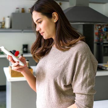 pregnant woman at home looking at phone