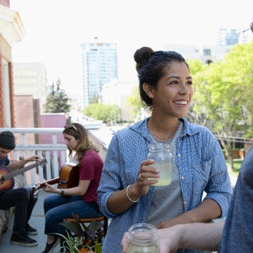 Millennial friends hanging out and playing guitars on apartment balcony