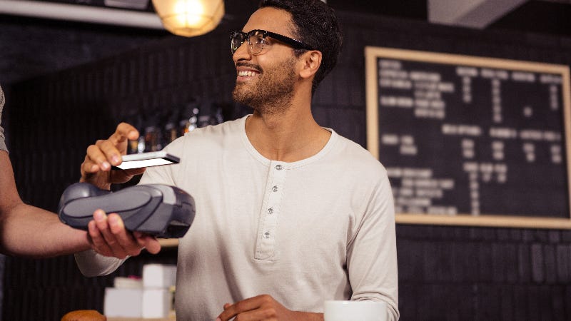 man at coffee shop paying with mobile wallet