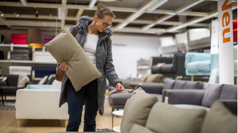 Woman looks at price tag of couch in furniture store