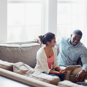 Shot of a young couple going through paperwork together on the sofa at home