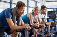 two men and a woman at the gym on stationary bikes