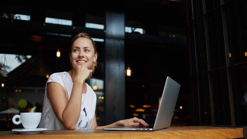 woman seated with computer and smiling