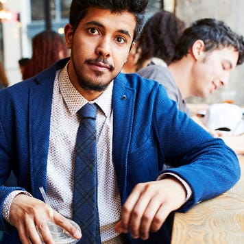 A man in a suit holds a coffee cup at a coffee shop