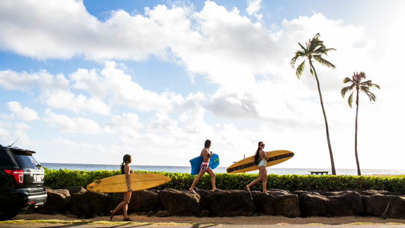 Surfers carrying surf boards to the Hawaiian beach