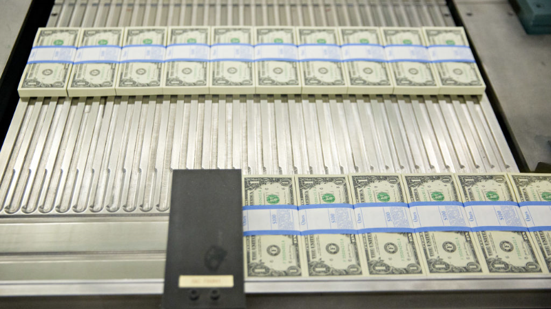 Stacks of dollars bills moving through a machine at the U.S. Bureau of Engraving and Printing