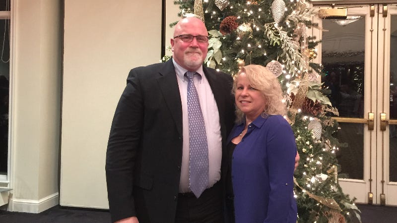 Christopher Lond and his wife stand by a Christmas tree