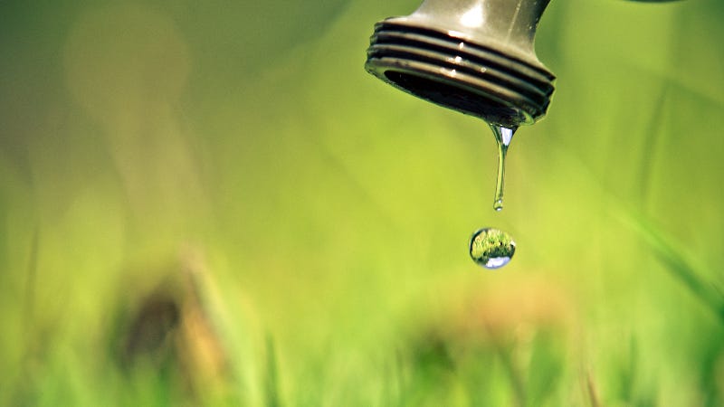 A single drop of water falls from a water spigot