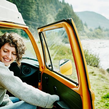 Smiling woman on road trip stepping out of van