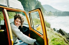 Smiling woman on road trip stepping out of van