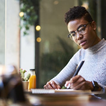 woman sitting at table writing in notebook