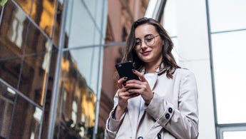 woman walking outside while looking at phone
