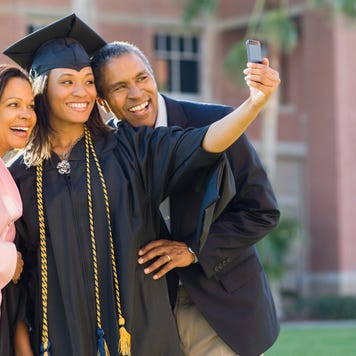 A young graduate woman takes a selfie with her parents
