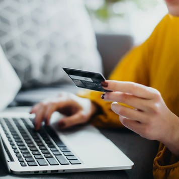 close up of hand holding credit card and typing on computer
