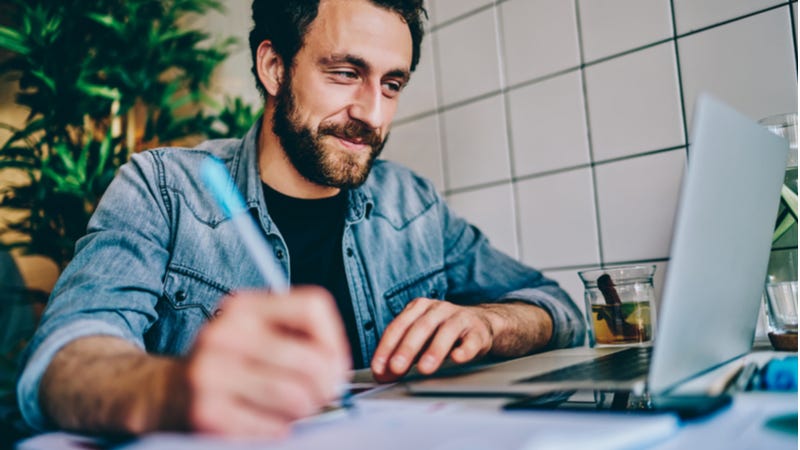 Bearded man happily working on laptop in cafe