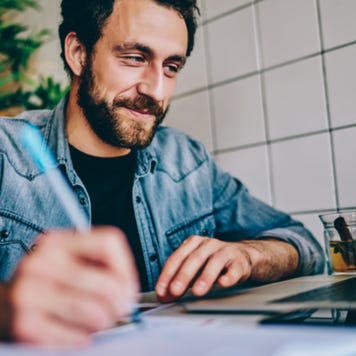 Bearded man happily working on laptop in cafe