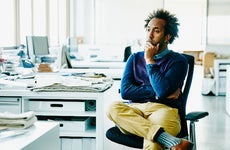 An African-American man sits a work desk with a thoughtful look