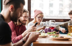 Group of young friends use smartphones to transfer funds for shared lunch