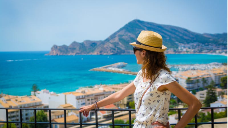 Female traveler gazes out over scenic seascape from balcony