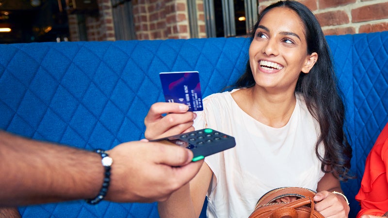 Young woman hands credit card to restaurant merchant