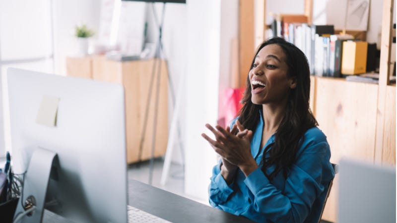 Young woman reacts to good news on computer monitor