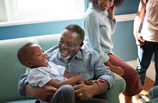 An African-American family and child laugh on a couch