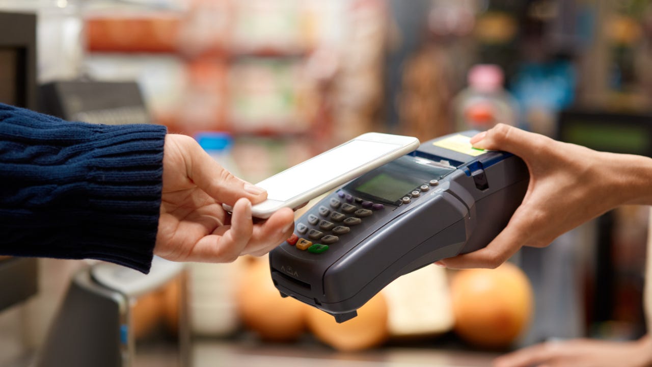 Person holding mobile phone to contactless card reader