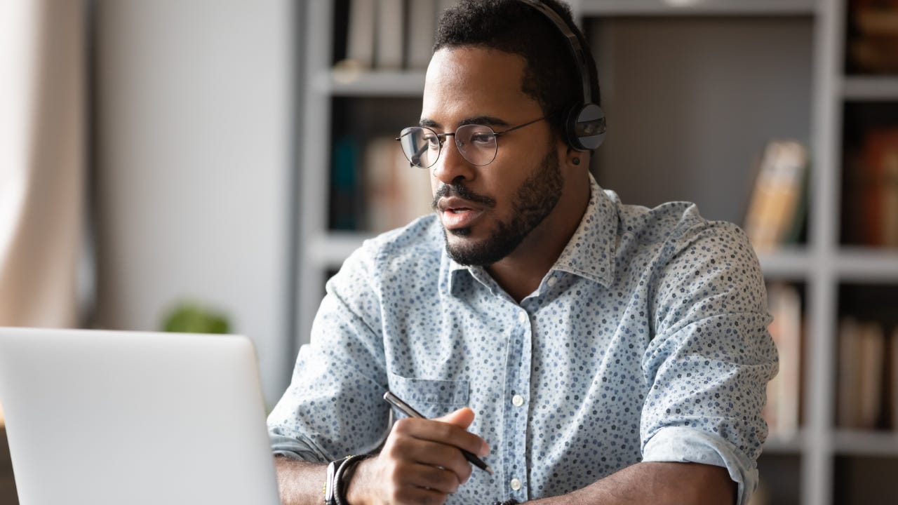 man sitting at desk in front of open laptop