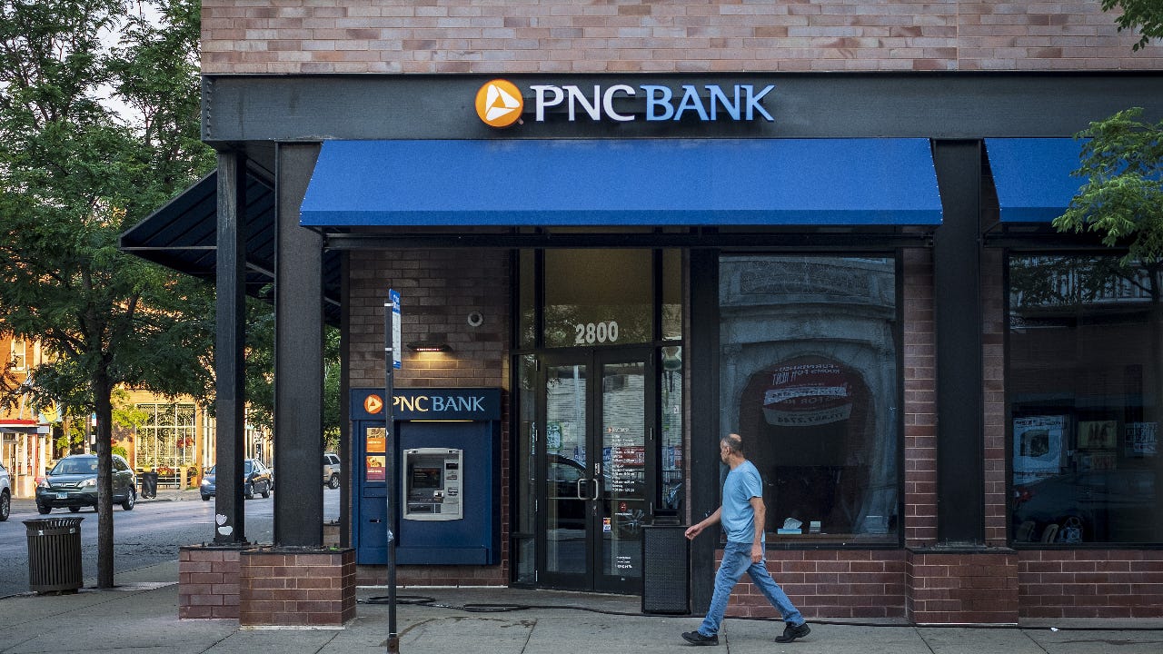 A pedestrian walks by a bank branch.