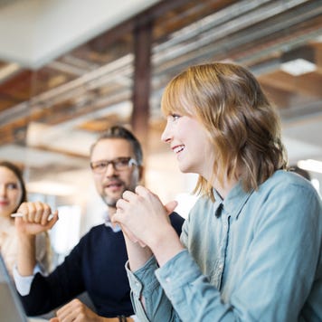A woman laughs with colleagues at an office table
