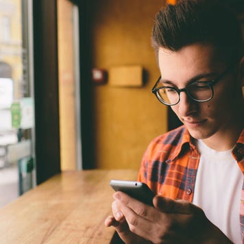 man sitting near window using cell phone