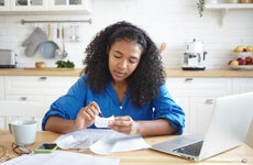 woman sitting at kitchen table looking at receipts