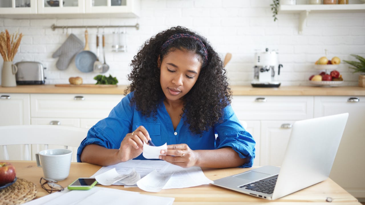 woman sitting at kitchen table looking at receipts