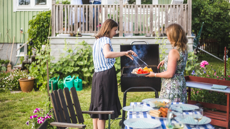 mother and daughter grilling in backyard of home