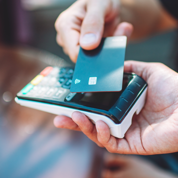 Adult man paying with credit card at cafe, close-up of hands with credit card and credit card reader