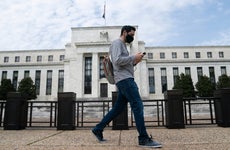 A man wearing a mask walks past the U.S. Federal Reserve building in Washington D.C.