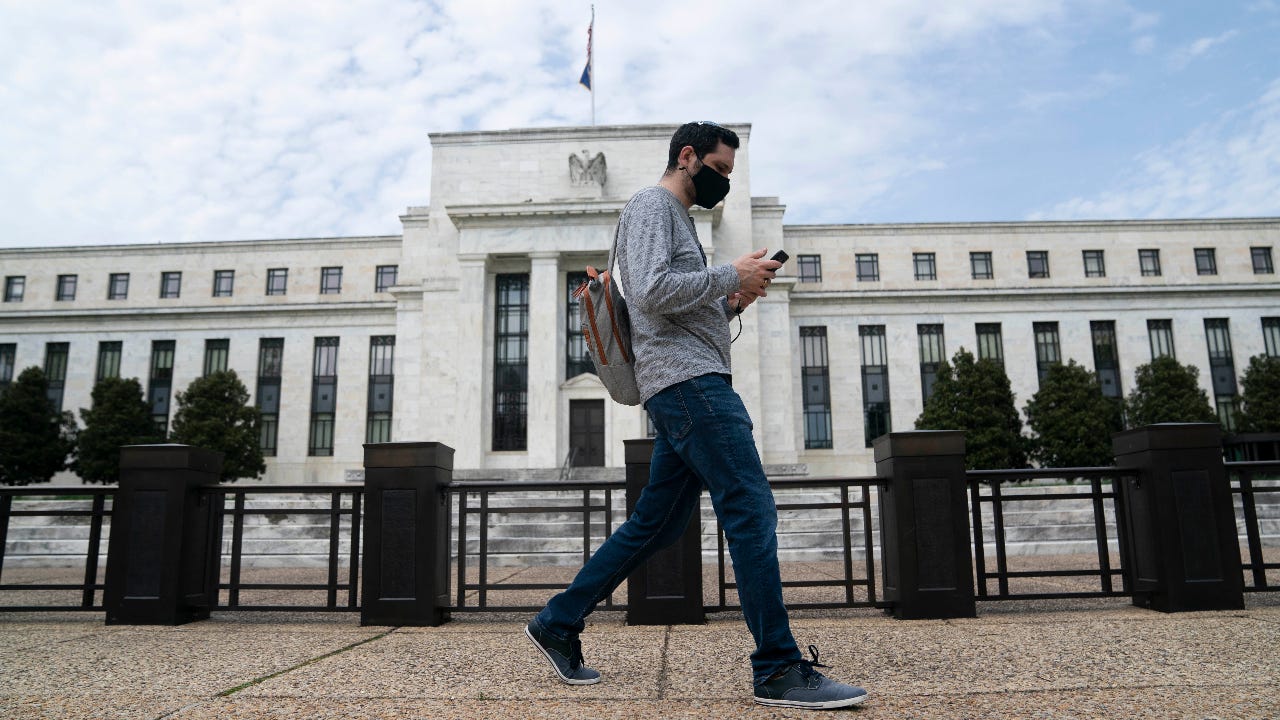 A man wearing a mask walks past the U.S. Federal Reserve building in Washington D.C.