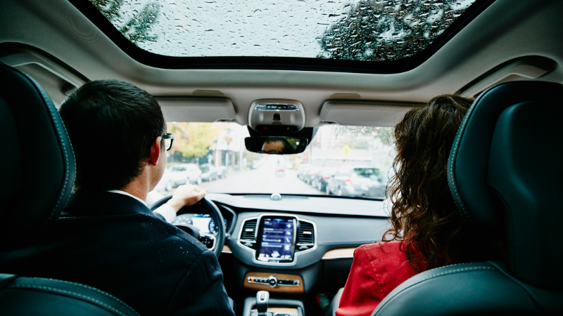 man and woman driving in car on rainy day