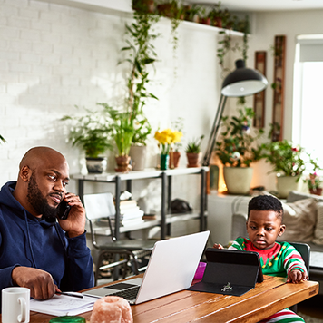 Father on phone call and working with son watching tablet