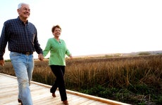 Older white couple walks down boardwalk