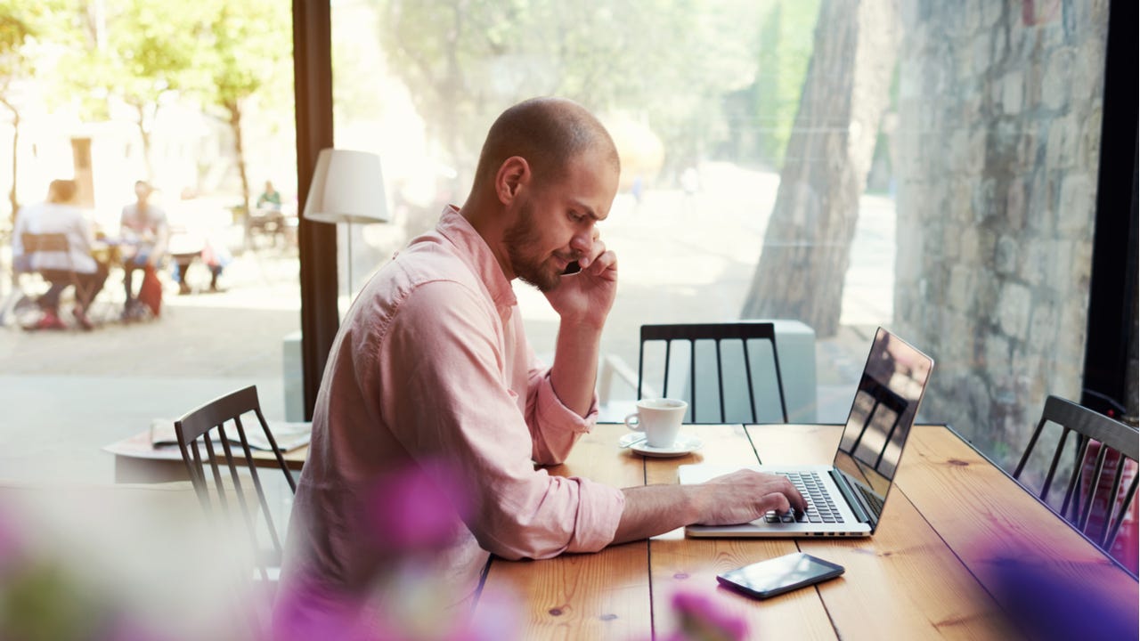 Man working on a computer while talking on the phone.