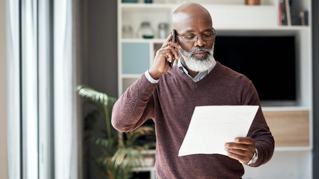 An older African-American man talks on the phone in his home