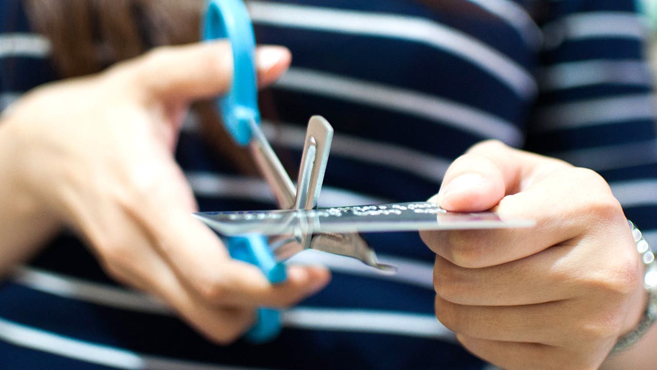 Woman cutting an old credit card with scissors
