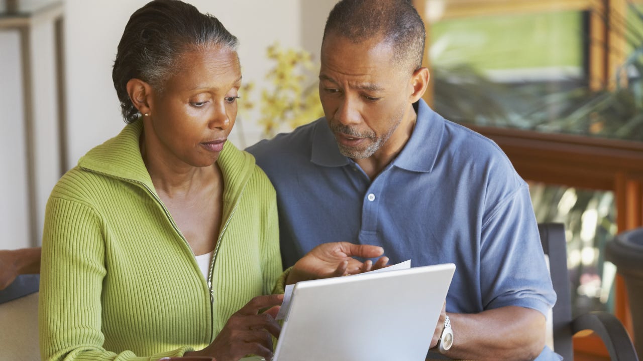 A senior, African-American couple look at a laptop together.