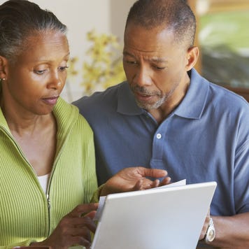 A senior, African-American couple look at a laptop together.