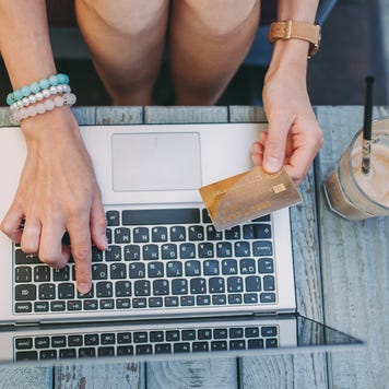 Person using computer and holding credit card