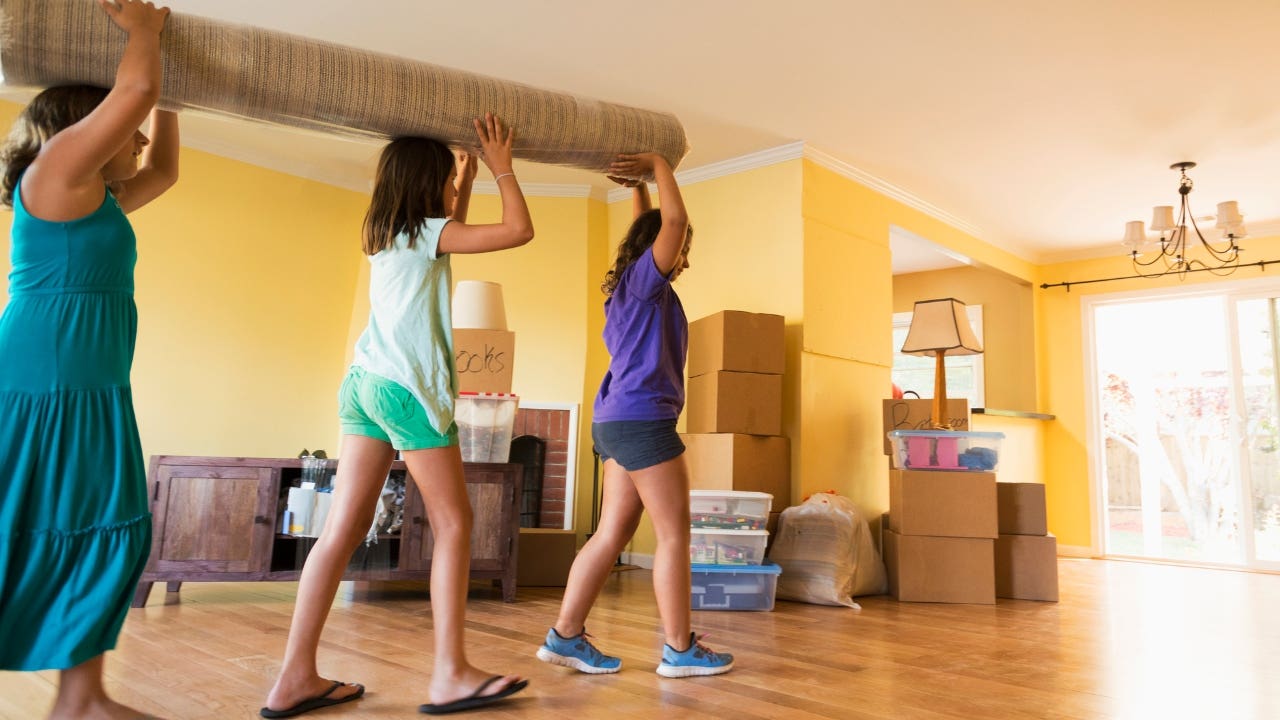 Children carrying carpet as they move into new house