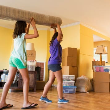 Children carrying carpet as they move into new house