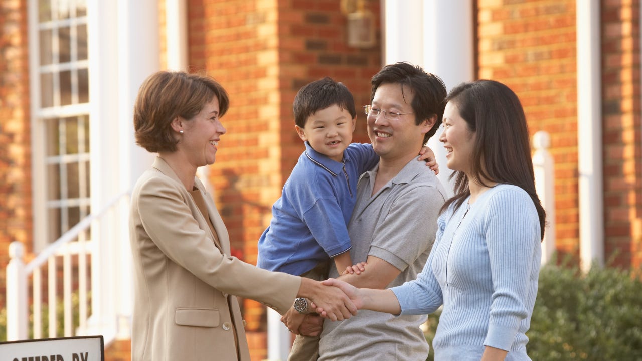 A young Asian couple and a child sign a real estate deal