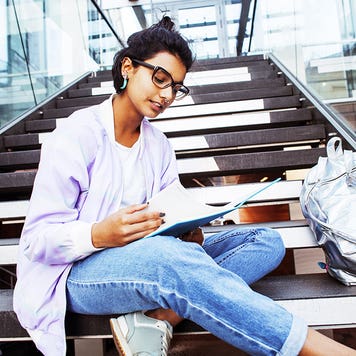 College student sits on steps while studying.